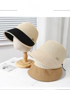 Detailed close-up of straw woven sun hats with metal fashion label and chin straps