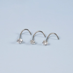 Macro shot of three stainless steel nose studs with clear zircon and curved S-shape posts