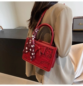 Detail of red bridal handbag featuring a 3D bow and delicate floral embroidery texture