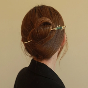 Détail d'une épingle à cheveux bambou dorée avec des feuilles imitation jade vert