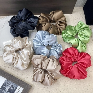 Flat lay of colorful satin silk scrunchies in black, brown, red and pastel tones