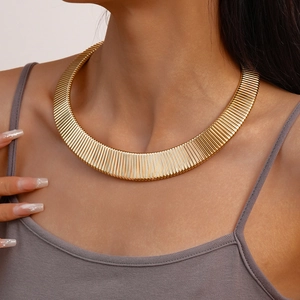 Bold golden metal choker necklace with vertical striped texture in a minimalist geometric style