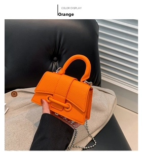 Close-up of orange mini hourglass bag with lychee texture and silver beaded chain strap