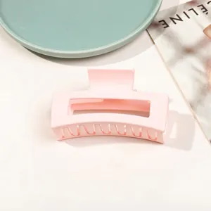 Detail view of large matte pink hair claw clip with hollow rectangle design on tray