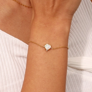 Detailed close-up of golden chain bracelet featuring a heart opal pendant and crystals