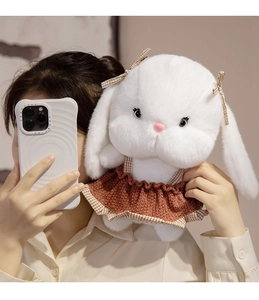 Detail of white plush rabbit doll wearing a knit dress held in a warm lifestyle setting