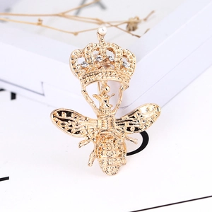 Gros plan sur une broche abeille dorée avec couronne, perles et cristaux étincelants