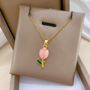 Detail of a luxury gold tulip necklace with pink flower and green leaves on a jewelry pad