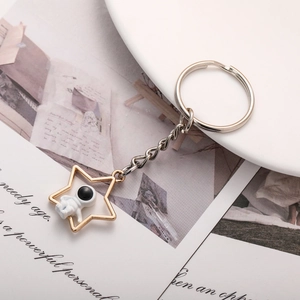 Macro detail of gold star-shaped keychain with miniature astronaut on book pages
