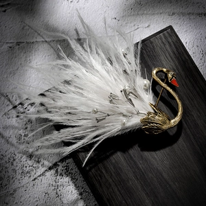 Vintage golden swan brooch with white feathers and pearls on a dark wood stand