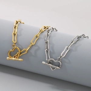 Detail of gold and silver clip chains with heart OT toggles on grey display pillar