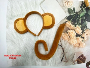 Detail shot of plush monkey ear headband and curled tail set on a soft white background