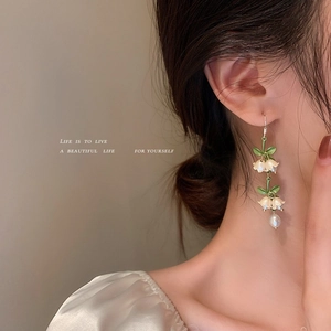 Close-up of lily of the valley earrings with green enamel leaves and white flowers