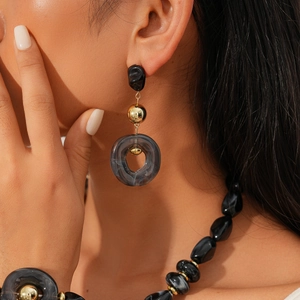 Detail of retro earrings with black beads and dark grey marble acrylic ring texture