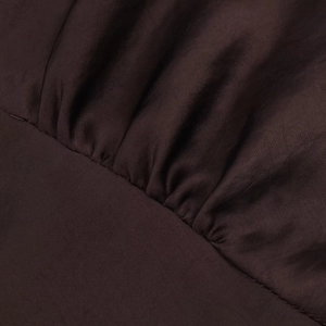 Macro detail of deep coffee satin fabric showing fine stitching and elegant pleat texture