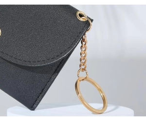 Detail of black lychee grain leather wallet with fine stitching and gold keychain