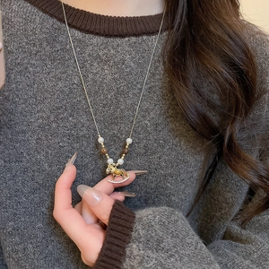 Detail of a rocking horse pendant with tiger eye stone and pearls on a gold necklace