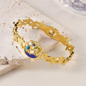 Détail macro du bracelet doré en acier inoxydable avec charme de palmier en émail tropical