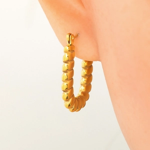 Close-up of elegant gold twisted hoop earrings worn by a model for a luxury look