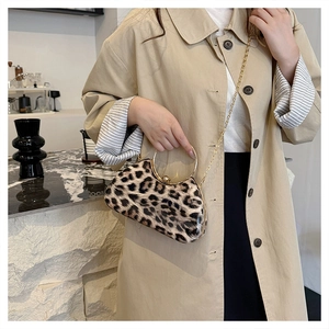 Leopard print clutch with gold ring handle and chain shown on a trench coat outfit