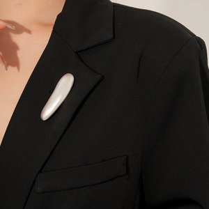 Close-up of a minimalist liquid metal bar brooch on a black suit lapel for women