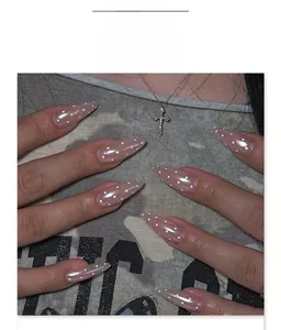 Detail of almond-shaped almond nails with nude pink base and white polka dot patterns