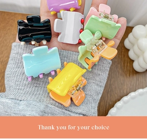 Detailed view of colorful candy-colored mini hair claws held in hand for size comparison