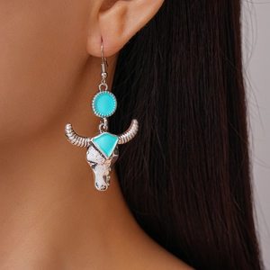 Close-up of retro bull head earrings with turquoise enamel inlay worn by a model