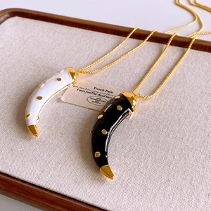 Detail of vintage horn pendants in black and white enamel on a golden chain necklace
