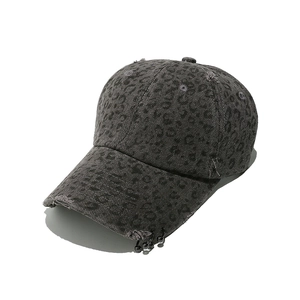 Detail of distressed leopard print baseball cap with metallic rings and punk style holes