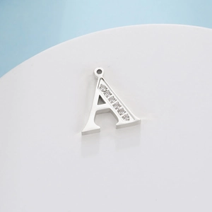 Close-up of a silver titanium steel letter A pendant with sparkling diamond inlay