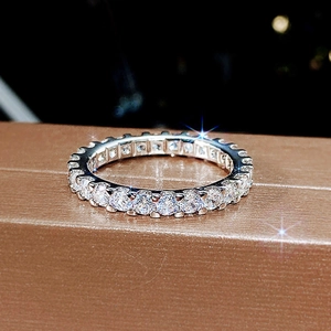 Sparkling silver eternity ring with round-cut pavé zircons on a textured bronze surface