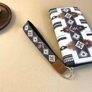 Ethnic geometric pattern long zipper wallet with wristlet strap on a minimal background