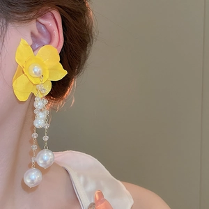 Close-up of long yellow fabric flower tassel earrings with white pearls on a model