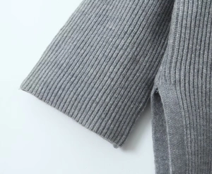 Macro detail of grey knit sweater showing ribbed cuffs and side slit hem craftsmanship