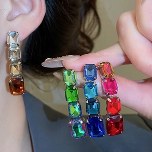 Close-up of square-cut crystal drop earrings in brown, green, blue, and pink colors