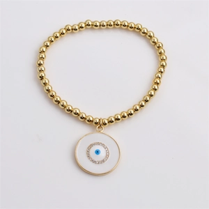 Detail of gold beaded stretch bracelet with blue enamel evil eye charm and zircons