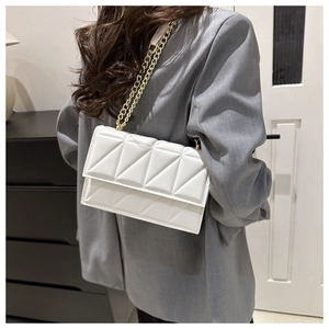 Chic white quilted crossbody bag with gold chain strap worn on woman's shoulder