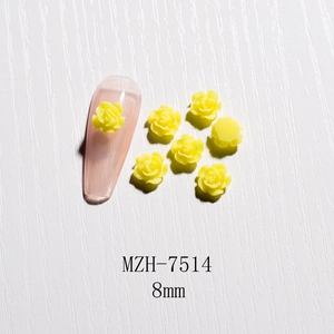 Detailed view of 8mm yellow resin rose nail art charms on white wood background