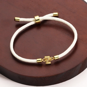 Detail of white braided bracelet featuring a sparkling zircon letter Z gold pendant