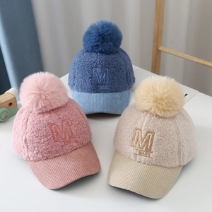 Close-up of children's teddy fleece baseball caps with pompom and M BABY embroidery