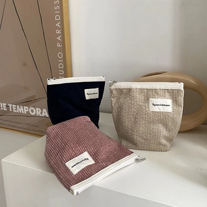 Detailed close-up of corduroy makeup bags in navy, beige, and pink with sturdy white zippers
