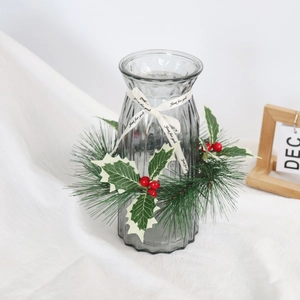 Grey textured glass vase with Christmas pine needle ring and berry decor on white fabric