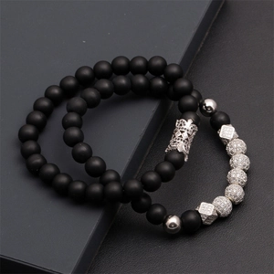 Close-up of black matte lava stone beads and silver crown charm on a men's bracelet set