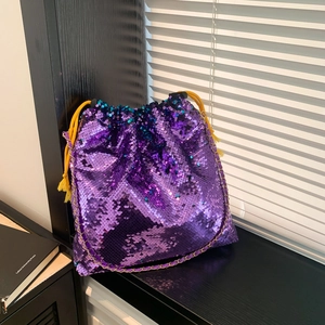 Detail of purple sequin bucket bag featuring yellow drawstring tassels and gold chain strap