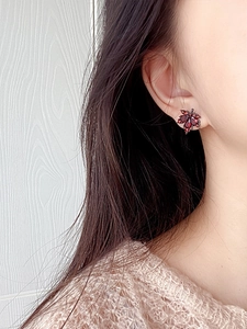 Detailaufnahme von retro roten Ahornblatt-Ohrsteckern an einem Modell im Herbststil