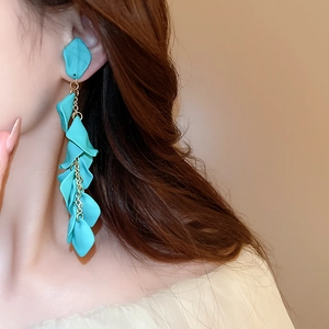 Macro side view of blue petal tassel clip-on earrings worn by a model in soft light