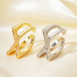 Detailed view of criss-cross zircon rings in gold and silver finish on silk fabric
