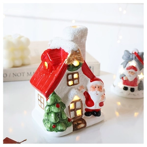 Cozy glowing ceramic Christmas house ornament with warm LED light on holiday table