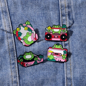 Cute green frog enamel pin set with music themes on blue denim fabric background